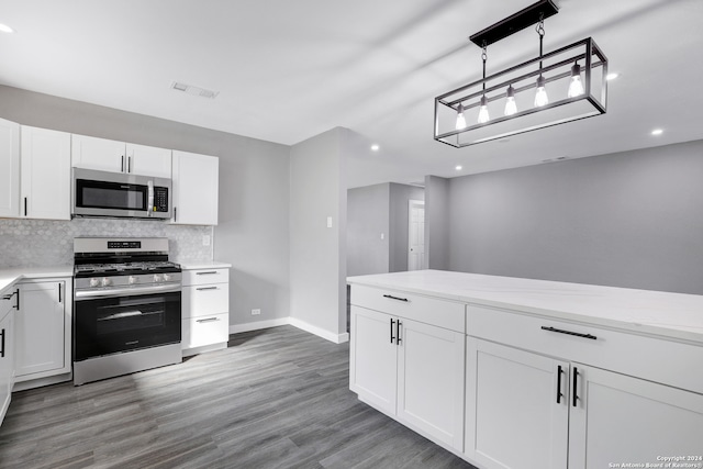 kitchen featuring appliances with stainless steel finishes, white cabinetry, hanging light fixtures, and dark hardwood / wood-style flooring