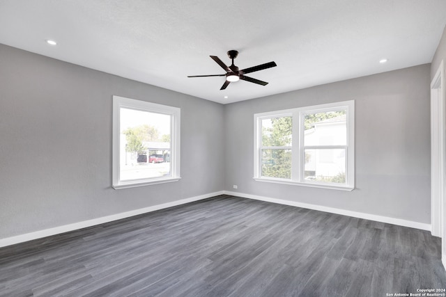 unfurnished room featuring a healthy amount of sunlight, dark wood-type flooring, and ceiling fan