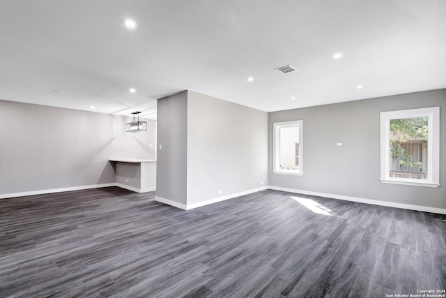 spare room with a notable chandelier and dark hardwood / wood-style floors