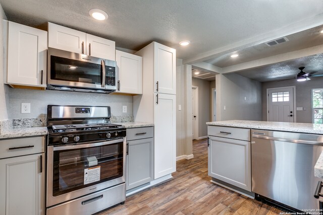 kitchen featuring white cabinets, ceiling fan, a textured ceiling, light hardwood / wood-style floors, and stainless steel appliances