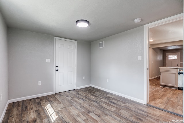 spare room with a textured ceiling and light wood-type flooring