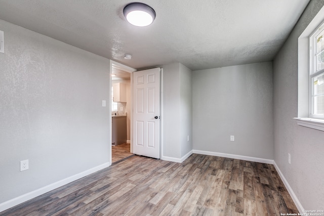 interior space with a textured ceiling and hardwood / wood-style floors