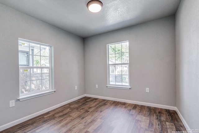 empty room featuring a wealth of natural light and dark hardwood / wood-style floors