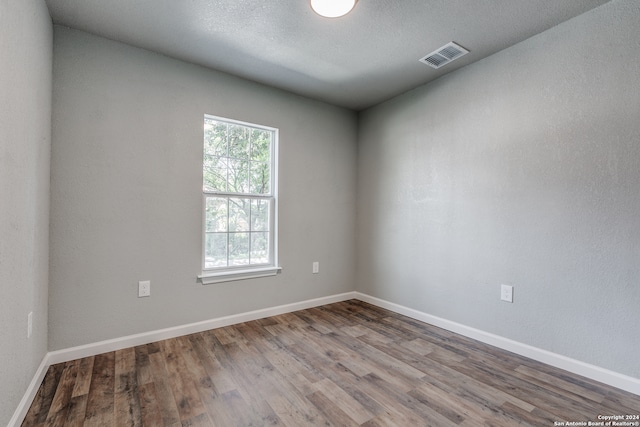 spare room with a textured ceiling and hardwood / wood-style floors