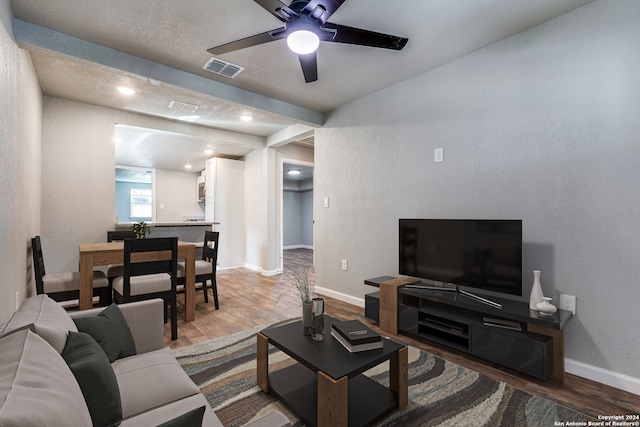 living room featuring hardwood / wood-style floors, a textured ceiling, and ceiling fan