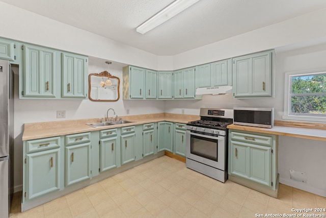 kitchen with a textured ceiling, stainless steel appliances, and sink