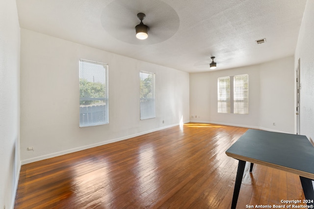 unfurnished living room with dark wood-type flooring, ceiling fan, and a textured ceiling