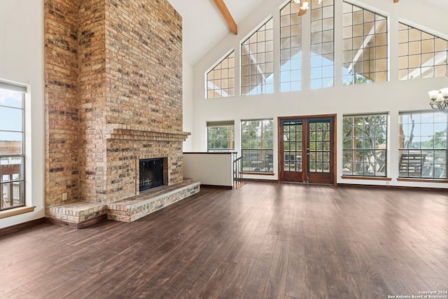 unfurnished living room featuring beamed ceiling, dark hardwood / wood-style flooring, high vaulted ceiling, and a brick fireplace