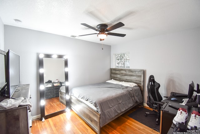 bedroom featuring ceiling fan, hardwood / wood-style flooring, and a textured ceiling