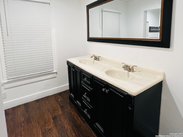 full bathroom featuring double vanity, wood finished floors, baseboards, and a sink