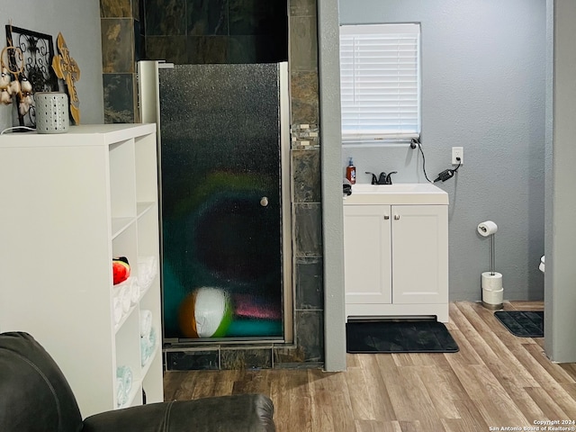 full bath with a sink, a shower stall, and wood finished floors