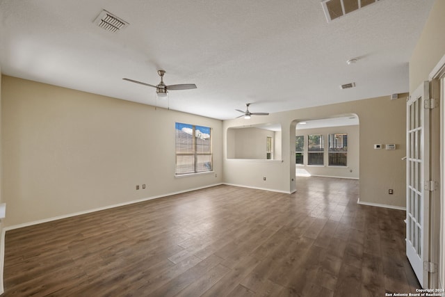 unfurnished room featuring a textured ceiling, ceiling fan, plenty of natural light, and dark hardwood / wood-style flooring