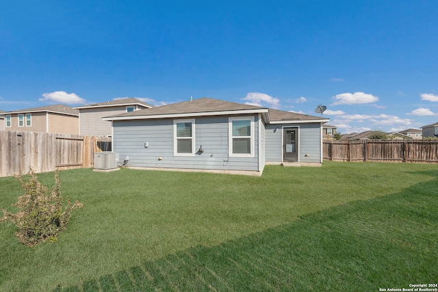 rear view of property with a yard and central air condition unit