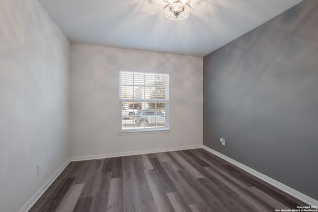 unfurnished room with a notable chandelier and dark hardwood / wood-style floors