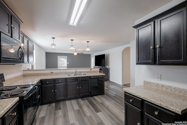 kitchen with light hardwood / wood-style flooring, hanging light fixtures, sink, black appliances, and a textured ceiling