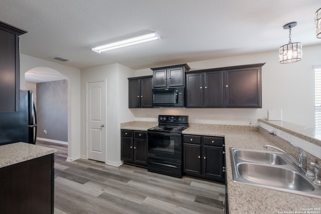 kitchen featuring hanging light fixtures, a textured ceiling, light hardwood / wood-style flooring, black appliances, and sink