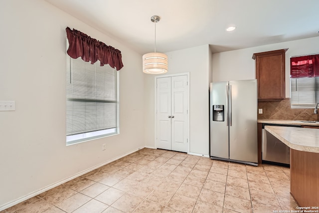 kitchen with decorative backsplash, stainless steel appliances, sink, light tile patterned floors, and decorative light fixtures