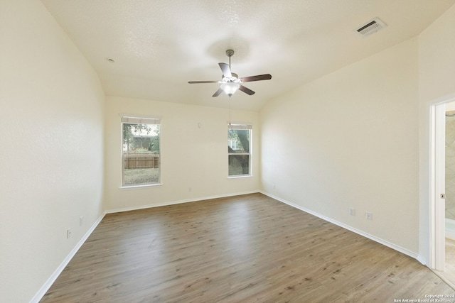 empty room featuring lofted ceiling, a textured ceiling, wood-type flooring, and ceiling fan