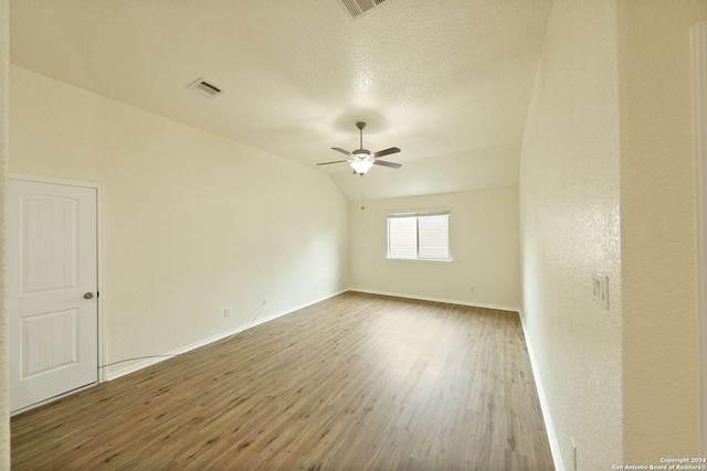 spare room featuring hardwood / wood-style floors, vaulted ceiling, a textured ceiling, and ceiling fan