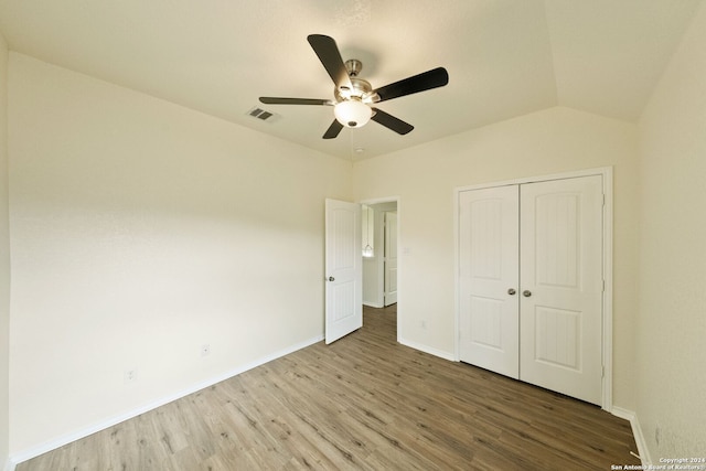 unfurnished bedroom featuring vaulted ceiling, hardwood / wood-style flooring, a closet, and ceiling fan