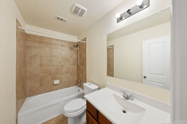 full bathroom with vanity, toilet, tiled shower / bath combo, and a textured ceiling