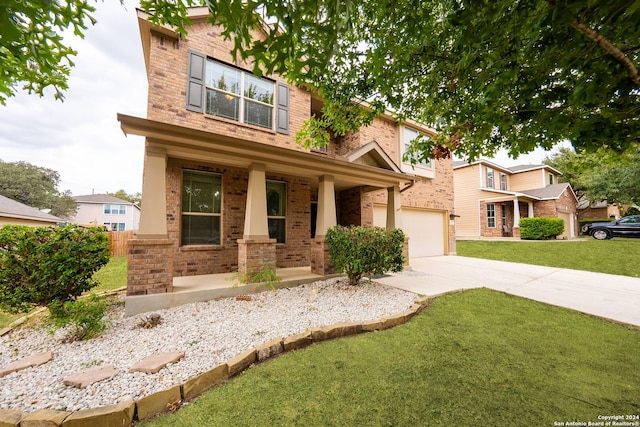 view of front of house featuring covered porch, a garage, and a front lawn