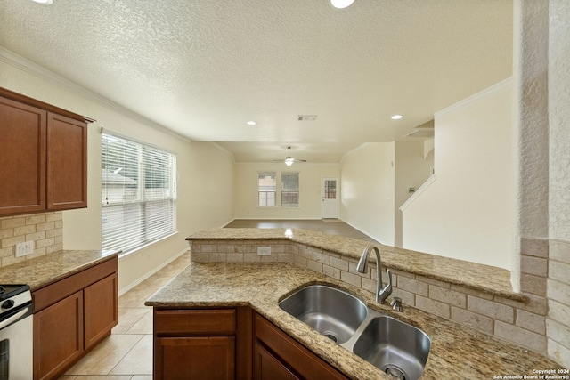 kitchen featuring kitchen peninsula, ornamental molding, sink, a textured ceiling, and ceiling fan