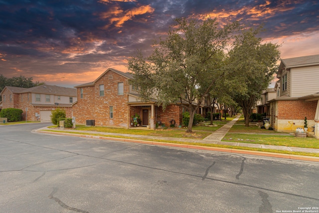 view of front of property featuring cooling unit, a yard, and a garage