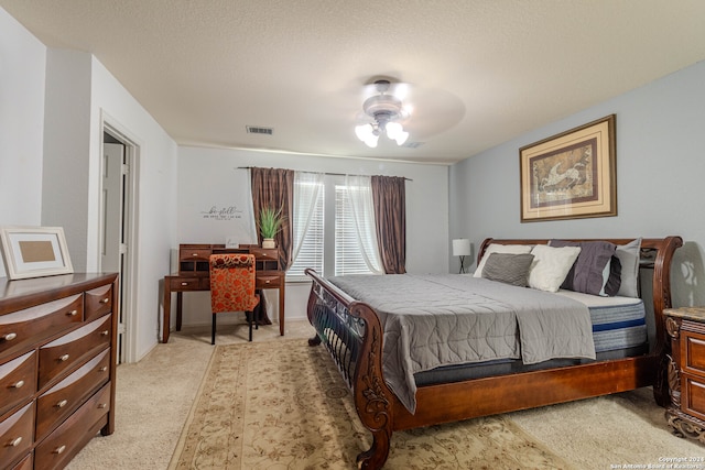 bedroom featuring light carpet, a textured ceiling, and ceiling fan