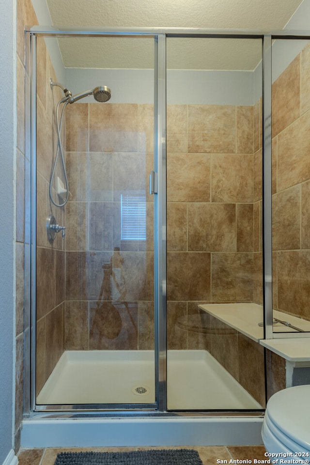 bathroom with a shower with door and tile patterned floors