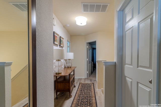 corridor with light hardwood / wood-style floors and a textured ceiling