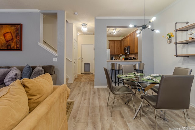 dining space featuring light hardwood / wood-style flooring, a chandelier, sink, and crown molding