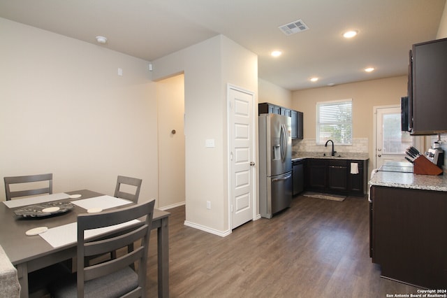 kitchen featuring sink, stainless steel fridge, dark hardwood / wood-style flooring, light stone counters, and tasteful backsplash