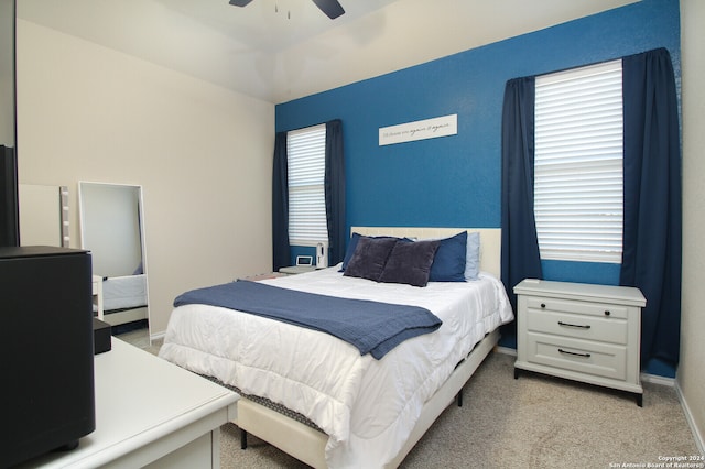 carpeted bedroom featuring multiple windows and ceiling fan