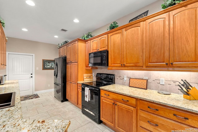 kitchen featuring light stone countertops, tasteful backsplash, black appliances, and light tile patterned floors