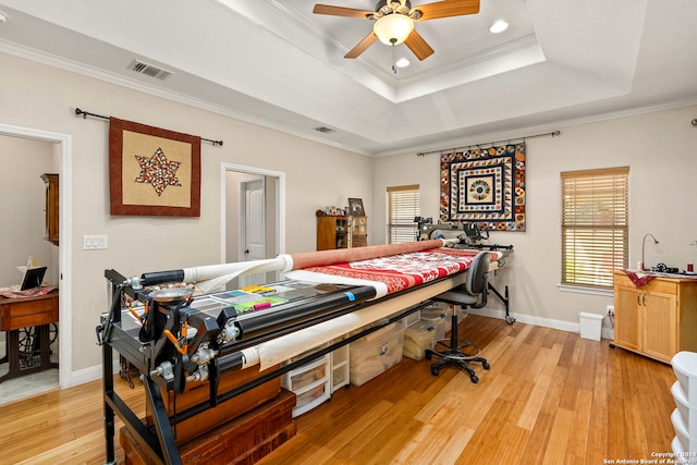 bedroom featuring light hardwood / wood-style floors, ornamental molding, a tray ceiling, and ceiling fan