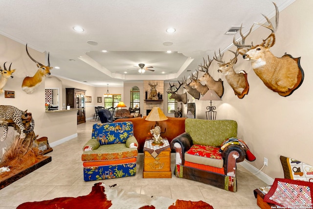 rec room with ceiling fan, ornamental molding, a tray ceiling, and light tile patterned floors