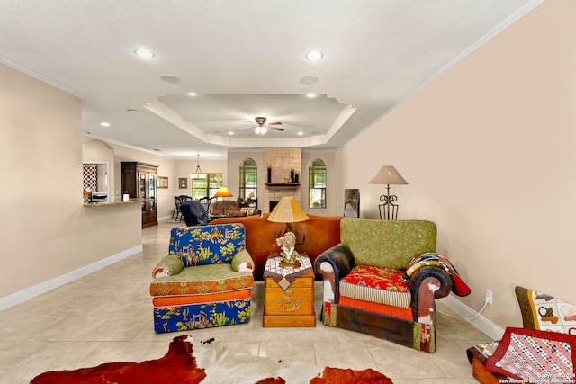 living room featuring ceiling fan, a raised ceiling, ornamental molding, and light tile patterned floors