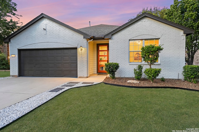 ranch-style home with a garage and a lawn