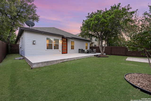 back house at dusk with a yard and a patio area