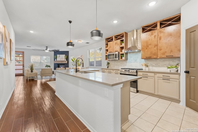 kitchen with sink, a large fireplace, stainless steel appliances, wall chimney exhaust hood, and decorative light fixtures