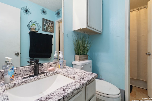 bathroom with vanity, a textured ceiling, toilet, and walk in shower