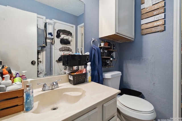 bathroom featuring vanity, toilet, and a textured ceiling