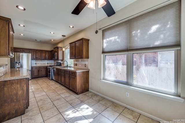 kitchen featuring appliances with stainless steel finishes, hanging light fixtures, tasteful backsplash, and plenty of natural light