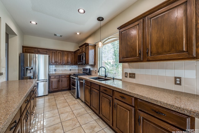 kitchen featuring backsplash, sink, pendant lighting, light tile patterned floors, and appliances with stainless steel finishes