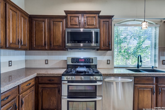 kitchen with appliances with stainless steel finishes, sink, and decorative backsplash