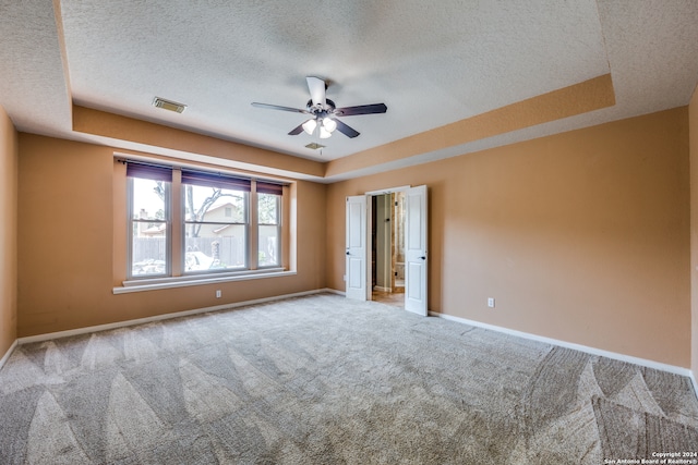 carpeted empty room featuring a textured ceiling, a tray ceiling, and ceiling fan