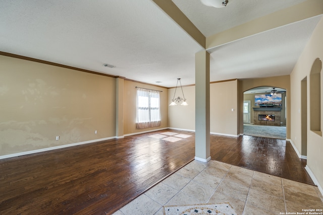 unfurnished room with ornamental molding, light hardwood / wood-style flooring, a textured ceiling, and ceiling fan with notable chandelier