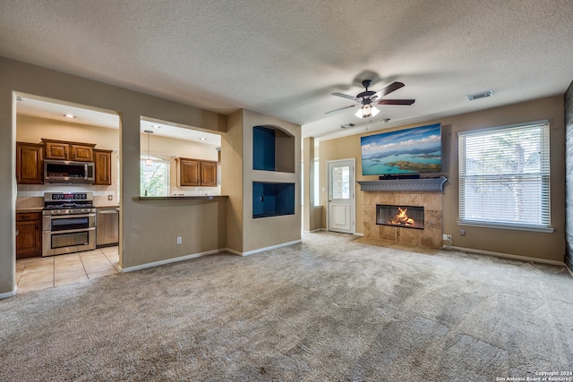 unfurnished living room with light carpet, a textured ceiling, a wealth of natural light, and ceiling fan