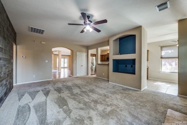 unfurnished living room featuring ceiling fan, a textured ceiling, and light colored carpet